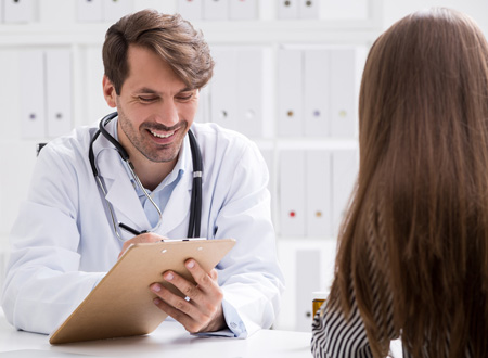 doctor with clipboard smiling and taking down patient's information