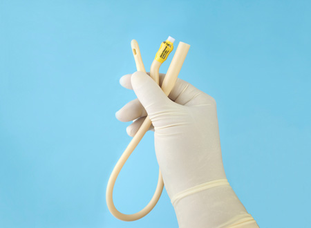 gloved hand holding catheter